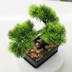 Close-up detail of artificial bonsai tree foliage and pebbles inside a modern black pot.