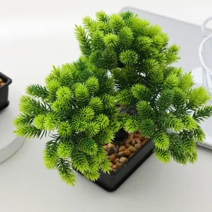 Detailed view of artificial bonsai plant with realistic pine needles and stones in pot.