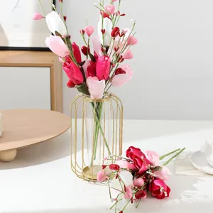 Close-up detail of artificial tulip bouquet with berries in gold wire glass vase for home decor.