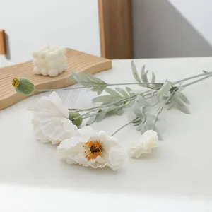Close-up detail of artificial poppy flowers with white petals and green flocked stems for decor.
