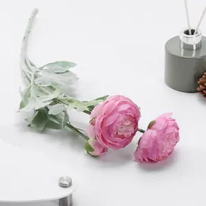 Detailed view of pink artificial ranunculus flower with frosted leaves for home decor.
