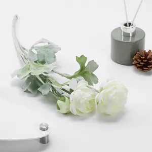 Close-up detail of artificial ranunculus flower with flocked green leaves and white blooms.