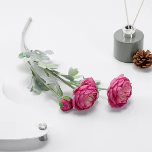 Close-up detail of artificial pink ranunculus flower with flocked leaves for wedding decor.