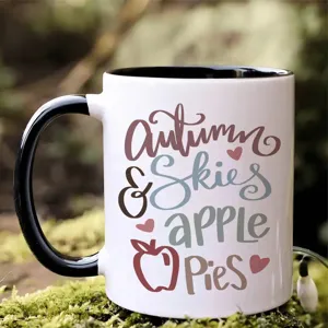 Taza de cafe de ceramica con estampado de otoo, asa negra y cuerpo blanco para oficina.