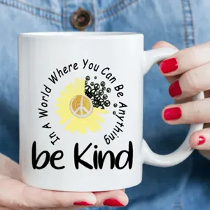 Nahaufnahme einer weißen Keramiktasse mit inspirierendem Zitat und Sonnenblumenmotiv.
