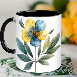 Détail de tasse en céramique avec motif de fleurs bleu et jaune style aquarelle et anse noire.