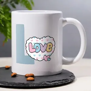 Close-up shot of white ceramic coffee mug featuring cute love design on slate desk top.