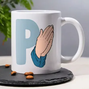 White ceramic coffee mug detail, featuring blue letter P and praying hands print design.