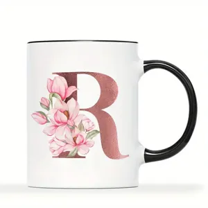 Nahaufnahme Detail einer Keramiktasse mit rosegoldenen Buchstaben R und rosa Magnolienblüten.