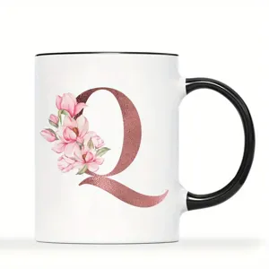 Weißer Keramikkaffeebecher mit schwarzem Henkel, roségoldener Buchstabe Q und rosa Blumen.