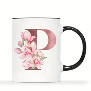Nahaufnahme einer weißen Keramik Tasse mit floralem Buchstaben P und schwarzem Henkel.