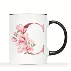 Detailansicht einer weißen Keramiktasse mit schwarzem Henkel und rosa Blumen Buchstabe C.