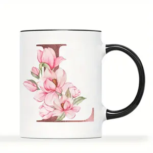 Nahaufnahme einer weißen Keramik Tasse mit schwarzem Henkel und Blumen Design Buchstabe L.