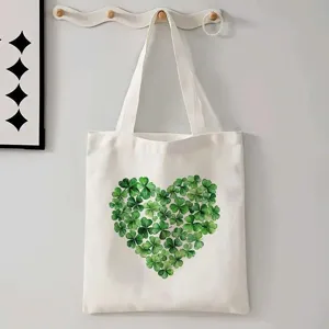 Detailansicht der weißen Canvas-Tragetasche mit grünem Kleeblatt-Herz-Print an Wandhaken.