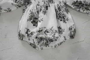 Detail view of infant baby girl floral print smocked long sleeve romper crawler clothing.