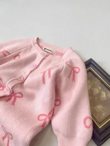 Baby girl pink knit cardigan romper with cute bow pattern and buttons close-up detail.