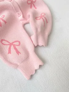 Pink knit baby romper with charming bow patterns, long sleeves, comfortable infant clothing.
