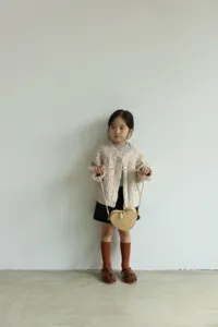 Dettaglio scena cardigan in maglia per bambini, look autunnale con borsa a cuore