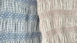 Baby girl smocked romper fabric detail, cute plaid and striped infant clothing close up.