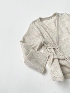 Detailopname van baby katoenen kimono top met kleurrijke stippen en strikbandjes.