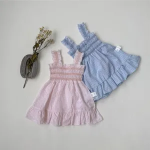 Detailed view of baby girl summer sleeveless smocked dresses in pink stripe and blue plaid patterns.