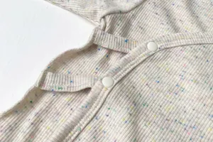 Close-up detail van baby geribd katoenen kimono top met zachte textuur en drukknopen.