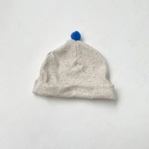 Detail van schattige baby muts, zachte gespikkelde rib katoen met blauwe pompon.