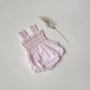 Infant pink checkered smocked romper detailed view with cute ruffles and convenient snaps.