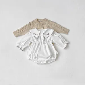 Vista dettagliata del cardigan in maglia per neonati e della tutina con ricamo fine.