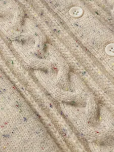 Primo piano dettaglio del cardigan in maglia beige per neonato con filato maculato.