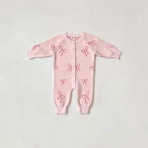 Detailed view of pink baby knit romper with cute bow patterns, cozy cardigan style for infants.