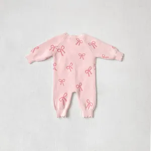 Close-up detail of pink baby knit romper showcasing cute bow patterns and soft sleeves.