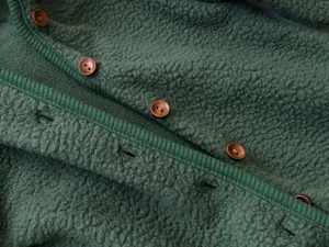Detail shot of green fleece baby romper fabric, featuring brown wooden buttons and ribbed trim.
