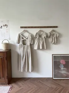 Detail view of matching embroidered linen family outfits featuring baby romper and toddler dresses.