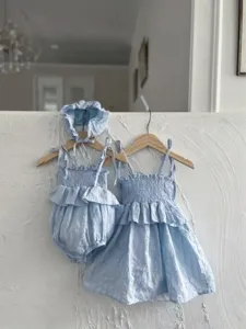 Gedetailleerd overzicht van baby meisje zomer lichtblauwe katoenen gesmokte jurk en romper.