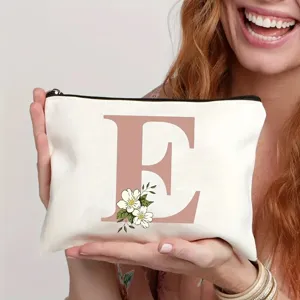 Gros plan détail de la trousse de toilette en toile blanche avec lettre rose E et fleurs.