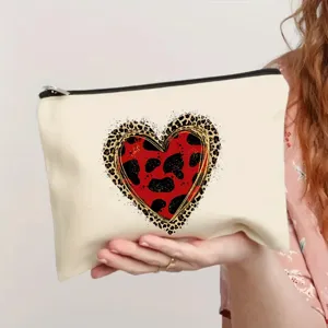 Closeup of canvas makeup pouch with red leopard heart print, zipper closure and portable design.