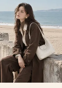 Sac a bandouliere en cuir blanc tisse vue detaillee sur une plage pittoresque.