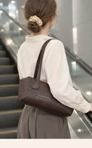 Detailed shot of a brown crocodile pattern leather Boston shoulder bag, commuter style.