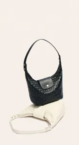 Détail de sac à main en cuir tressé, texture artisanale souple et présentation bicolore.