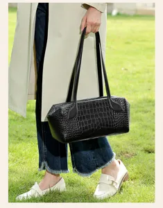 Close-up detail of black crocodile embossed leather Boston shoulder bag with dual straps.