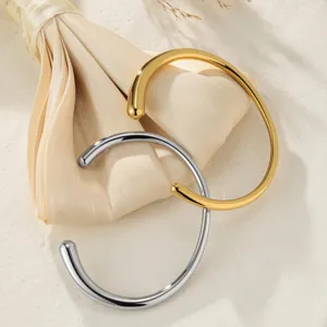 Detail shot of minimalist open gold and silver metal cuff bangles, elegant and sleek design.