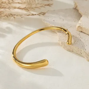 Close-up of minimalist gold open cuff bracelet showing polished metal surface and refined details.