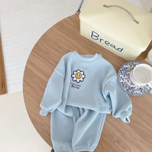 Detalle de conjunto de descanso acanalado azul claro para niños con parche de margarita.