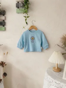 Vista detallada de sudadera de canalé azul claro para bebé de manga larga con diseño de margarita.