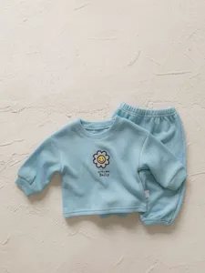 Detalle conjunto bebé acanalado, top manga larga azul claro y pantalón con bordado de margarita.