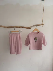 Primer plano detallado del conjunto informal rosa de canalé con bonito bordado de margarita.