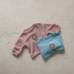 Vista detallada de sudadera de bebe de canal fino con bonito bordado de girasol sonriente.