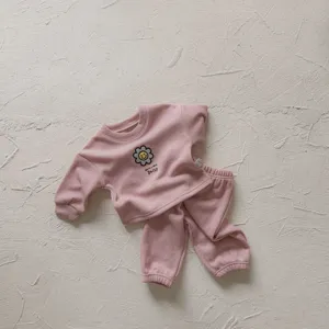 Detalle de conjunto de sudadera y pantalón acanalado rosa con bordado de margarita.