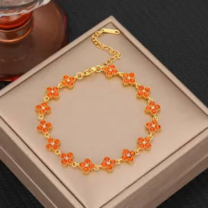 Exquisite gold-tone titanium steel clover bracelet featuring vibrant orange gemstone details.